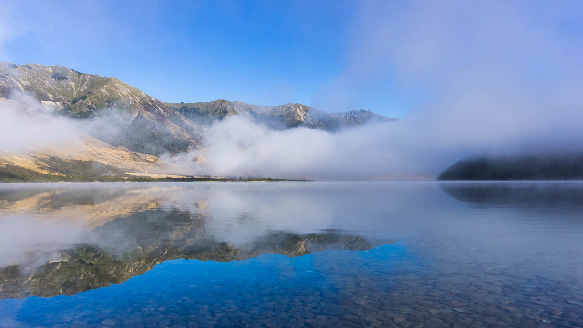 Early morning in New Zealand: clouds over the lake. Hills in the background