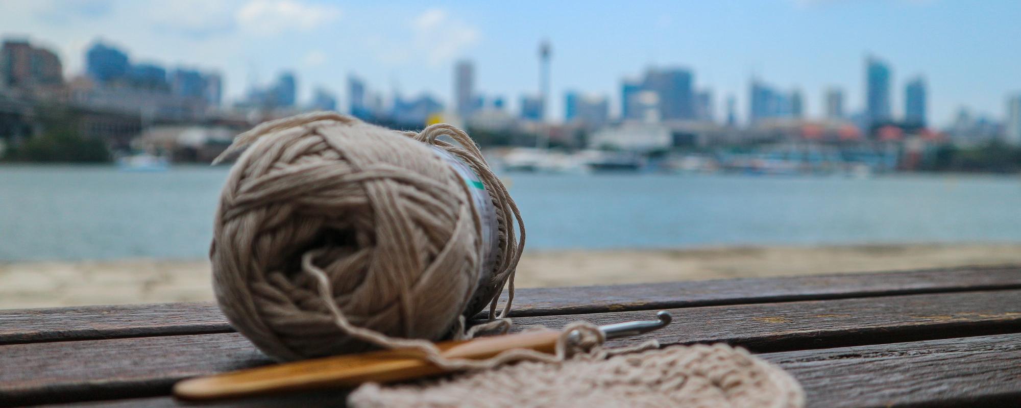 Yarn and crochet hookon a bench. Auckland skyline in the background