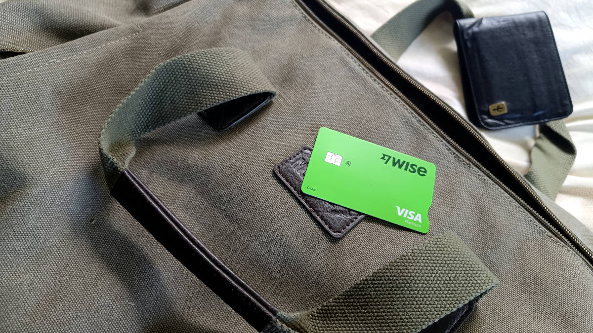 Wise debit card (green) lyimg on a bag (olive green) - it's time to pack for the next trip