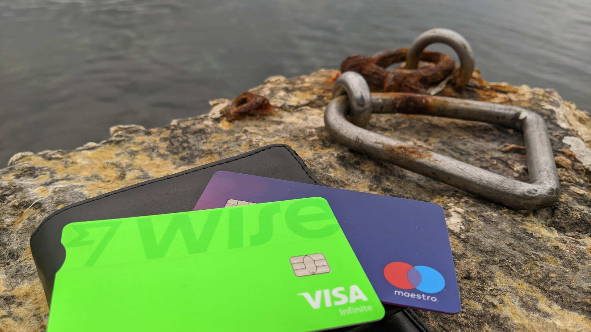 Two payment card lying on a rock close to water