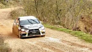 WRC rally car on a dusty road in Spain. The car just came around the bend, on the straight now