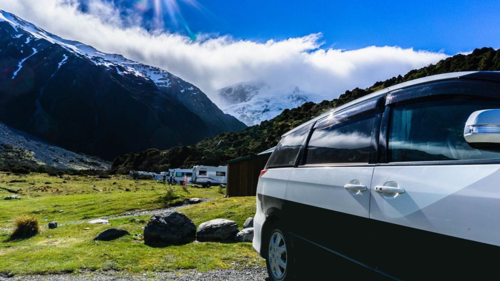 Variety of campervans and motorhomes at a campsite in New Zealand with snow-capped mountain in the background