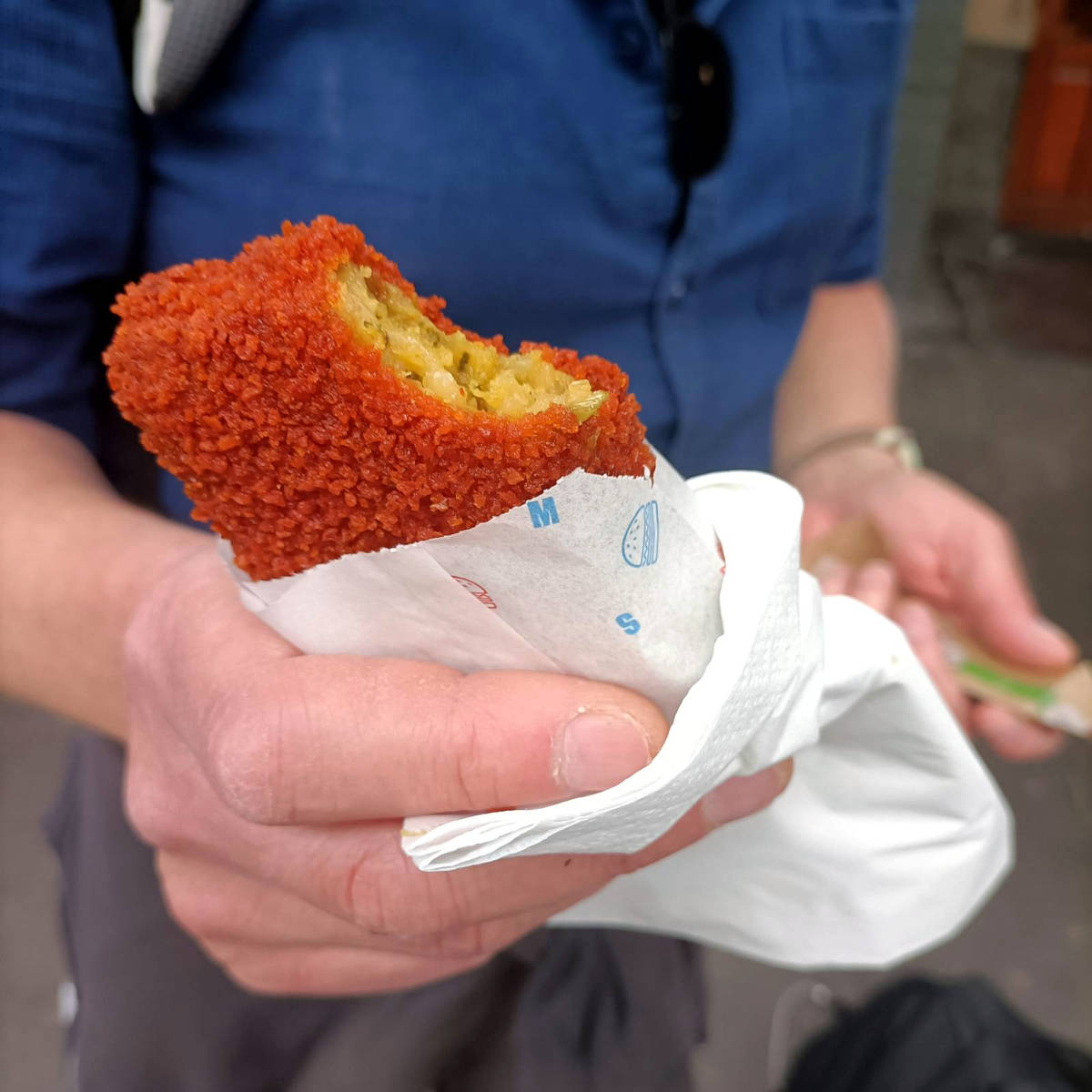 Close-up of a Dutch bamischijf (diep fried noodle patty) with one bite taken so you can see the noodles