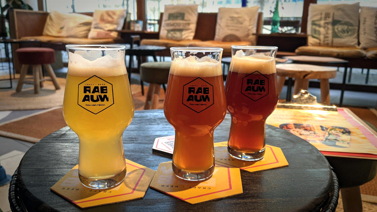 Three glasses filled with beer (Rabauw logo visible) on a table, look over the tap room