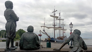 Jongens van de Bontekoe statues seen from behind, looking over the water - Sailing boat in the distance. Cloudy day.