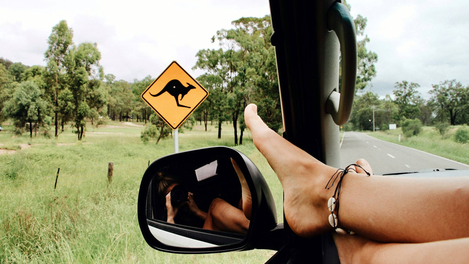 Road trip photo: passenger with feet close to open window and taking photo of the road and side mirror