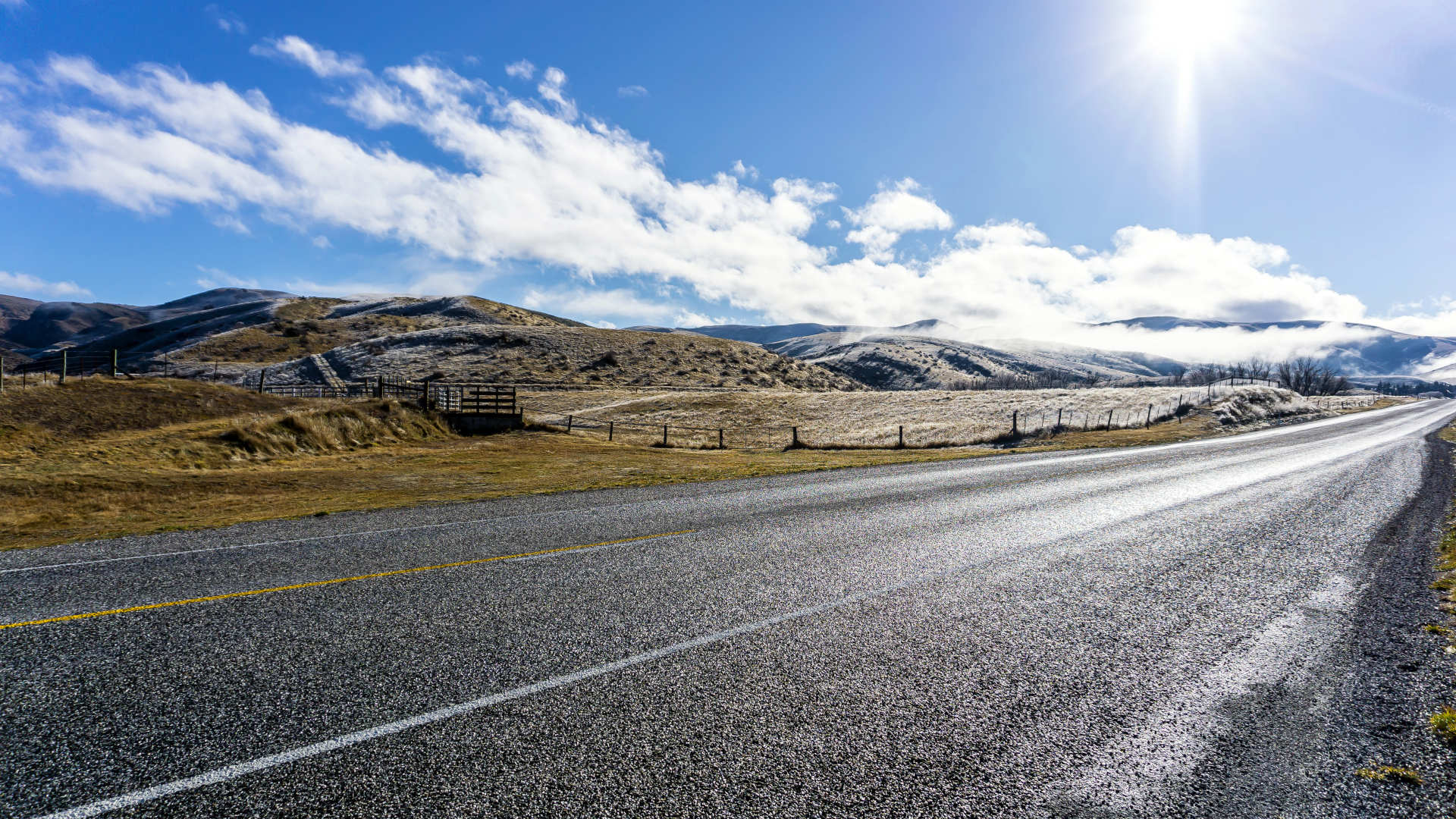 Sunny road trip day in New Zealand. Empty road, blue sky and frosty landscaoe