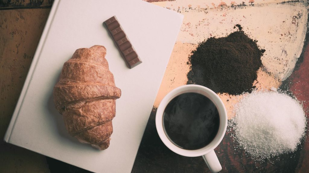 Photo from above of a croissant and a cup of coffee