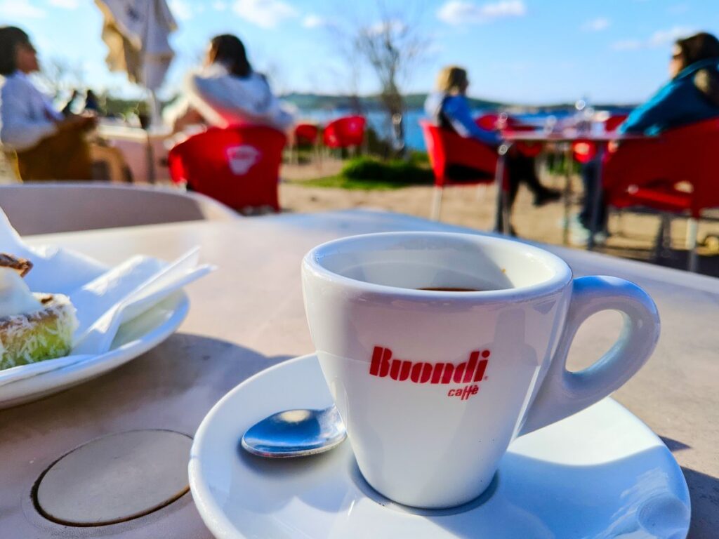 Close up of espresso cup with other people and the ocean in the background (photo taken in Malta)