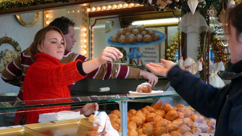Close-up of a person buying oliebollen - Dutch doughnuts - from a street vendor - food truck