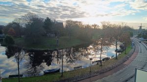 View from my room at Amrath Hotel in Alkmaar: sun rising, quiet road, water reflecting trees, windmill in the distance