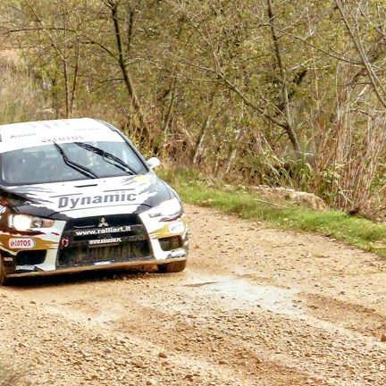 WRC rally car on a dusty road in Spain. The car just came around the bend, on the straight now